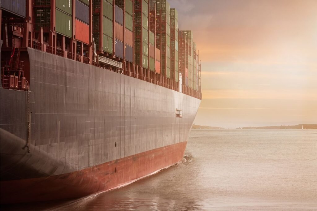 The Art of Drawing Readers In: Your attractive post title goes here A colossal cargo ship loaded with containers navigates through calm waters against a vibrant sunset sky.